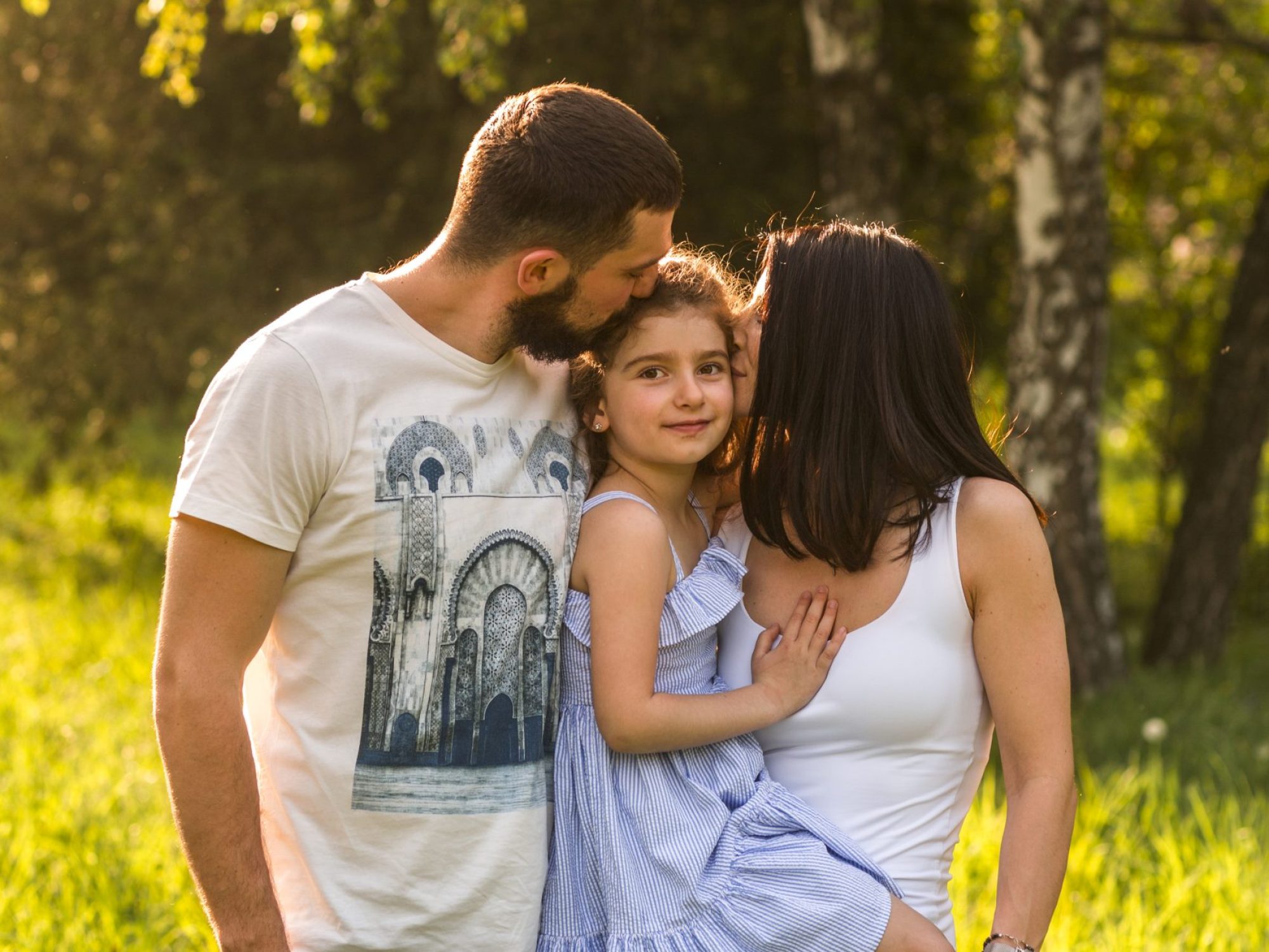 loving-parents-kissing-their-daughter-park