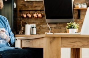 Smiling disabled freelance worker enjoying on lunch break with his dog while working at home.